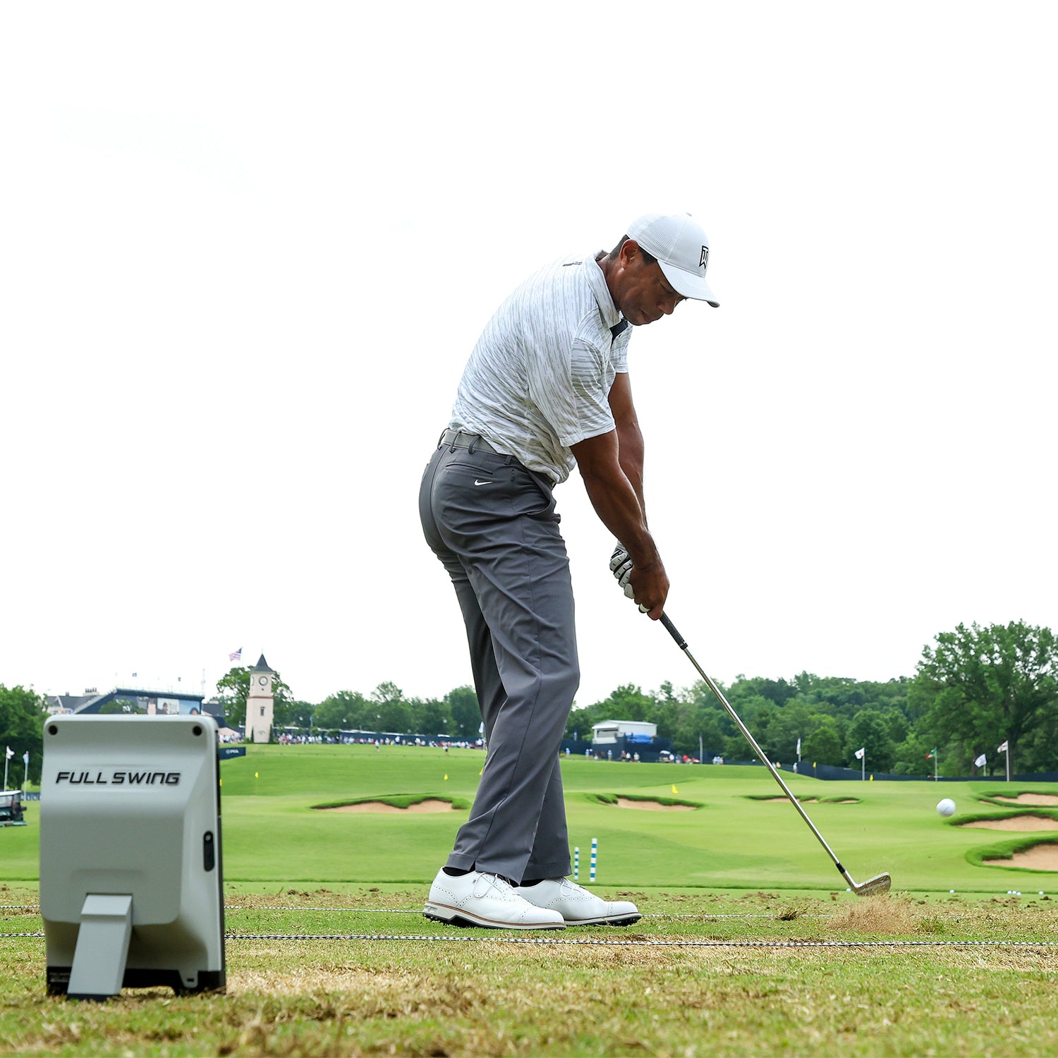 Golfer in action on a golf course with a 'Full Swing' cart in the foreground.