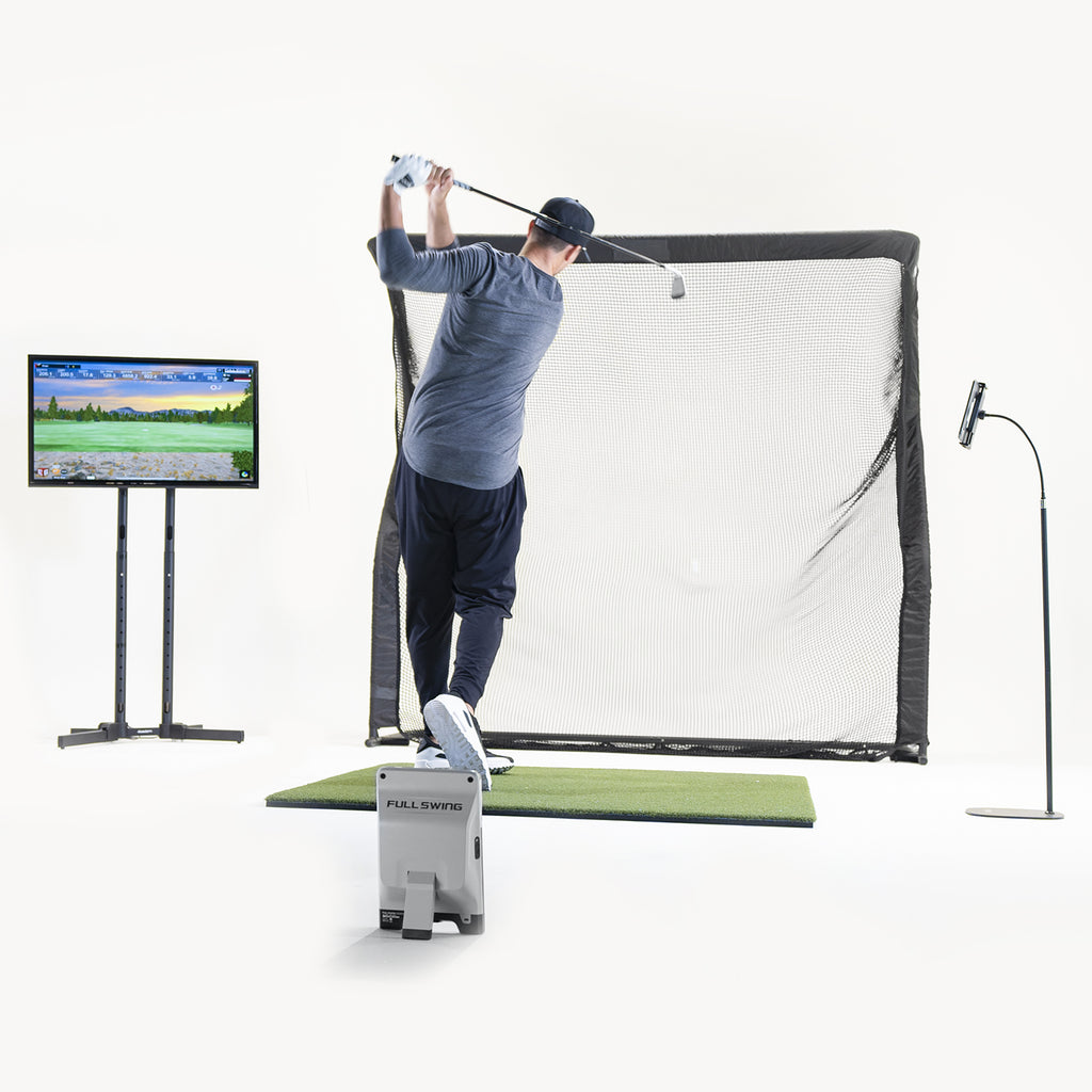 Person practicing golf swings on a simulator with a screen displaying a golf course.