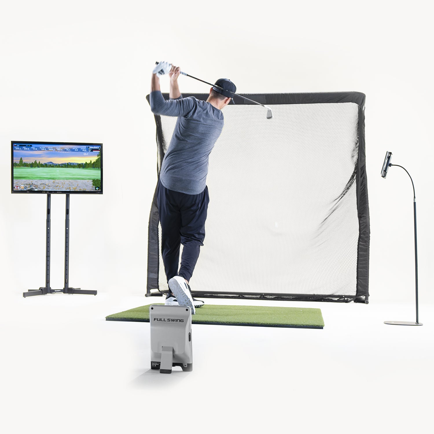 Person practicing golf swings on a simulator with a screen displaying a golf course.