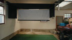 Indoor setting with a projector screen on the wall and a green mat on the floor.