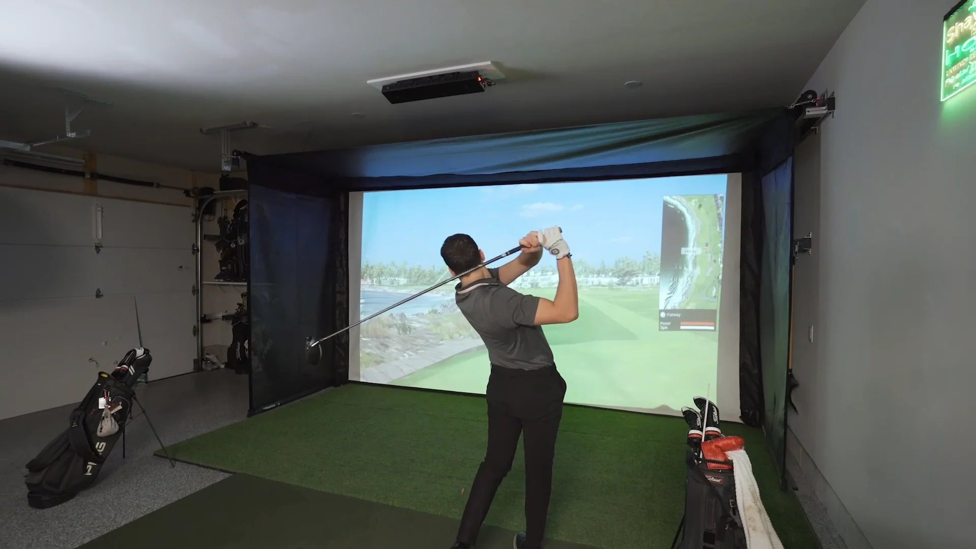 Person practicing golf swings in a home indoor simulator setup.