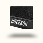 Black rectangular object with textured surface and 'UNEEEKOR' branding on a white background