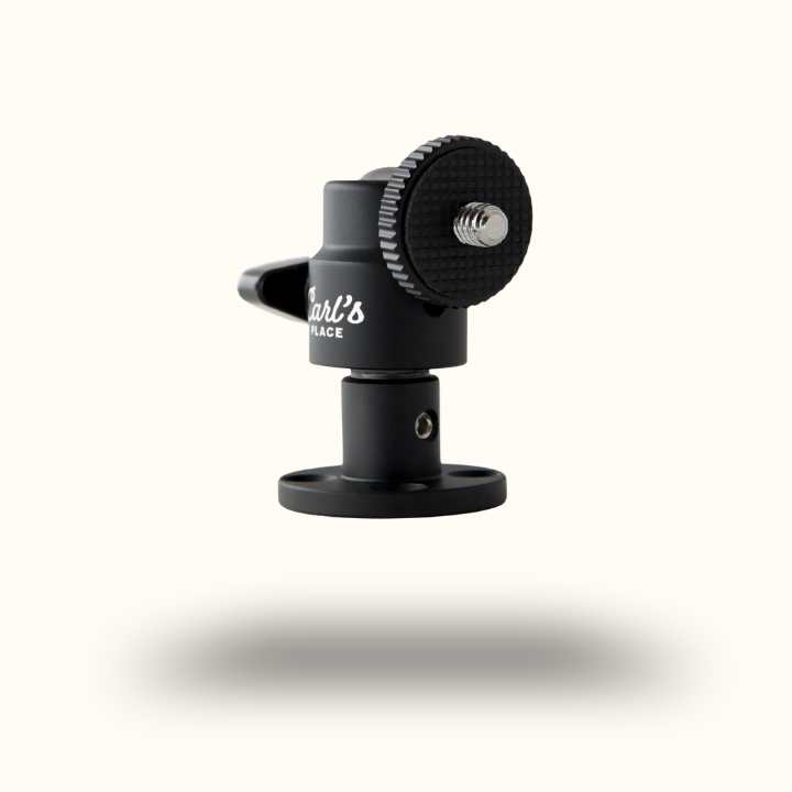 Black mounting bracket with a textured adjustment knob and a small metal screw, hovering above a soft shadow on a plain white background.