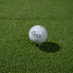 Golf ball with 'Carl's Place' branding on a green grass surface