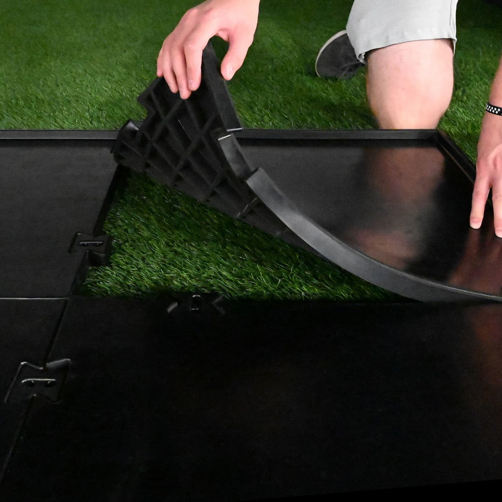 Person adjusting a black folding chair on artificial grass